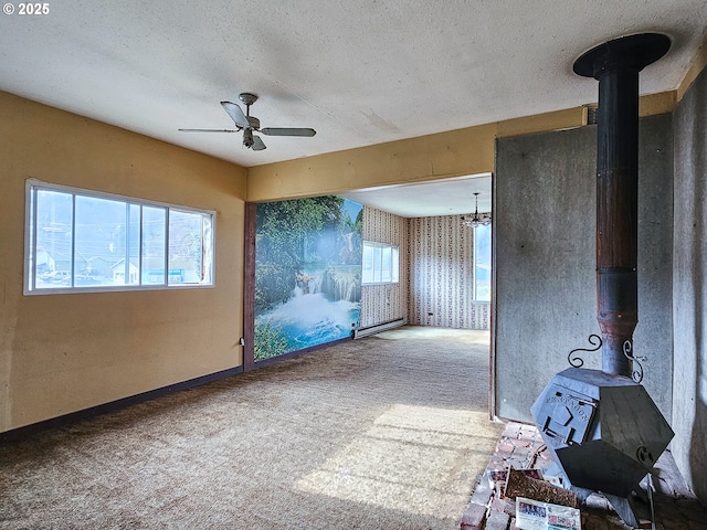 unfurnished room featuring ceiling fan, a textured ceiling, carpet, and a wood stove