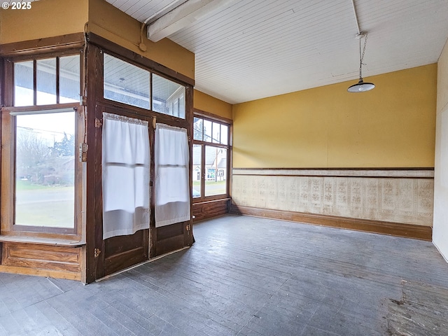 empty room with beamed ceiling and dark hardwood / wood-style flooring