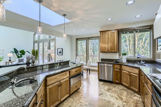 kitchen with dishwasher, sink, hanging light fixtures, and dark stone countertops