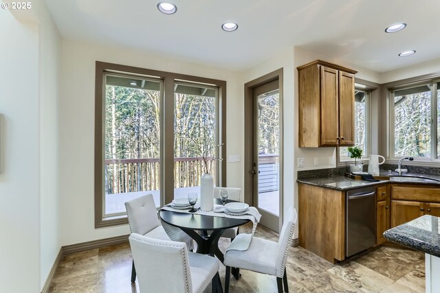 kitchen with dishwasher, sink, and dark stone countertops