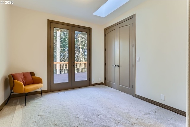 doorway featuring french doors, light colored carpet, and a skylight