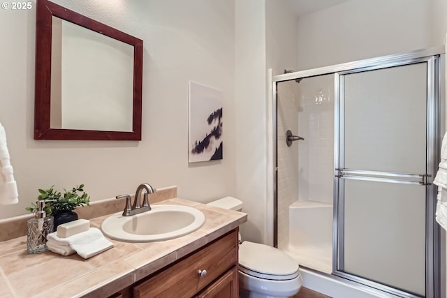 bathroom with an enclosed shower, vanity, and toilet