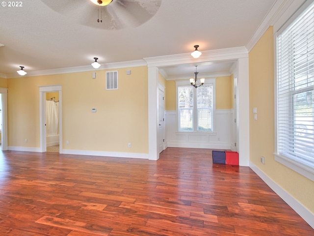 unfurnished living room with crown molding, dark wood-type flooring, and ceiling fan with notable chandelier