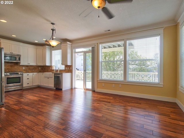 kitchen featuring dark hardwood / wood-style floors, decorative light fixtures, white cabinetry, backsplash, and stainless steel appliances