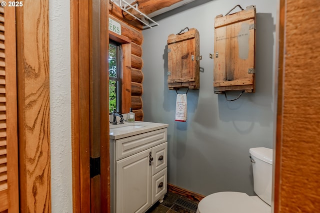 half bath with toilet, rustic walls, and vanity