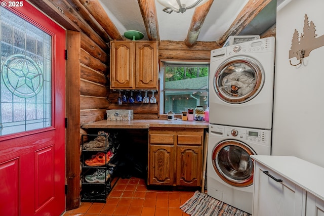 laundry area featuring tile patterned flooring, rustic walls, stacked washer and dryer, and cabinet space