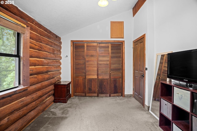 unfurnished bedroom with light colored carpet, rustic walls, vaulted ceiling, and a textured ceiling