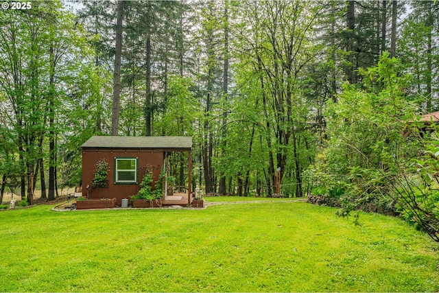 view of yard with an outdoor structure, a view of trees, and a shed