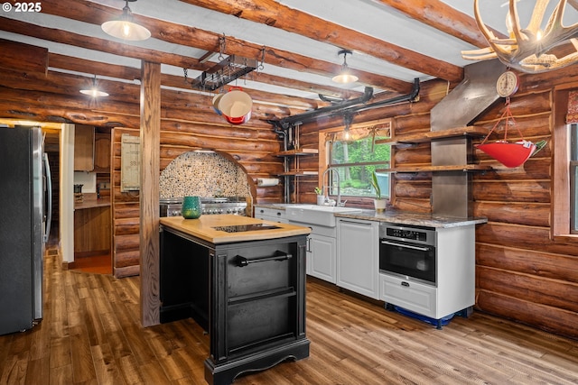 kitchen with open shelves, beamed ceiling, dark wood-style floors, a sink, and stainless steel appliances