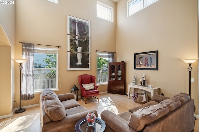 living area featuring a towering ceiling, wood finished floors, and baseboards