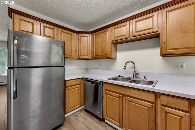 2117 Kauffman Ave, Vancouver, WA 98660 - kitchen with appliances with stainless steel finishes, a sink, light wood-type flooring, a textured ceiling, and light countertops