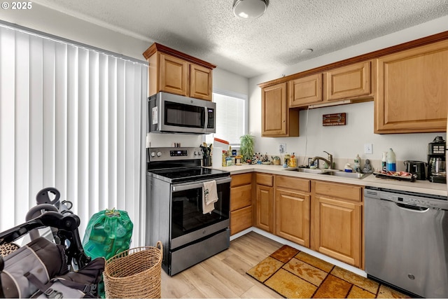 2117 Kauffman Ave, Vancouver, WA 98660 - kitchen with appliances with stainless steel finishes, a sink, light countertops, a textured ceiling, and light wood finished floors