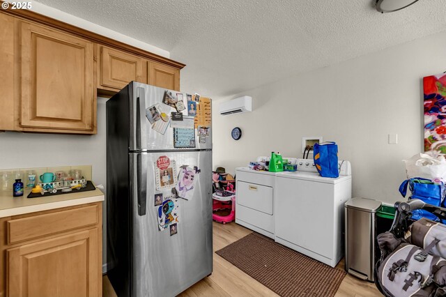2117 Kauffman Ave, Vancouver, WA 98660 - kitchen featuring freestanding refrigerator, independent washer and dryer, a wall mounted air conditioner, light wood-type flooring, and a textured ceiling