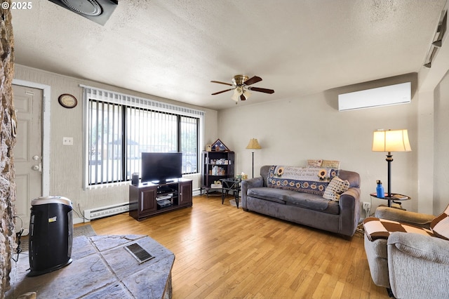 695 32nd St, Springfield, OR 97478 - living area featuring light wood-type flooring, a wall unit AC, a ceiling fan, a textured ceiling, and a baseboard radiator