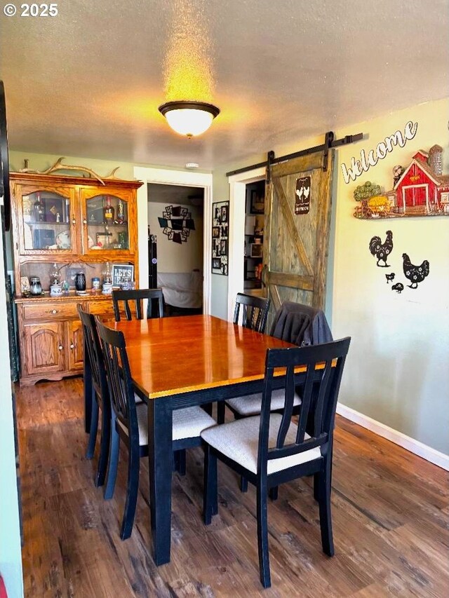 dining room with baseboards, a barn door, and dark wood-type flooring