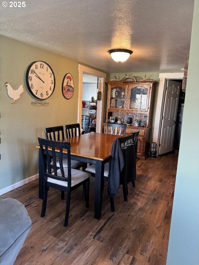 dining space featuring dark wood-style flooring, a textured ceiling, and baseboards