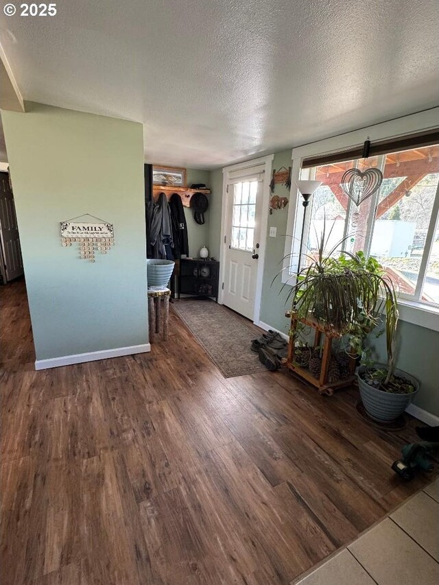 foyer entrance featuring baseboards, a textured ceiling, and wood finished floors