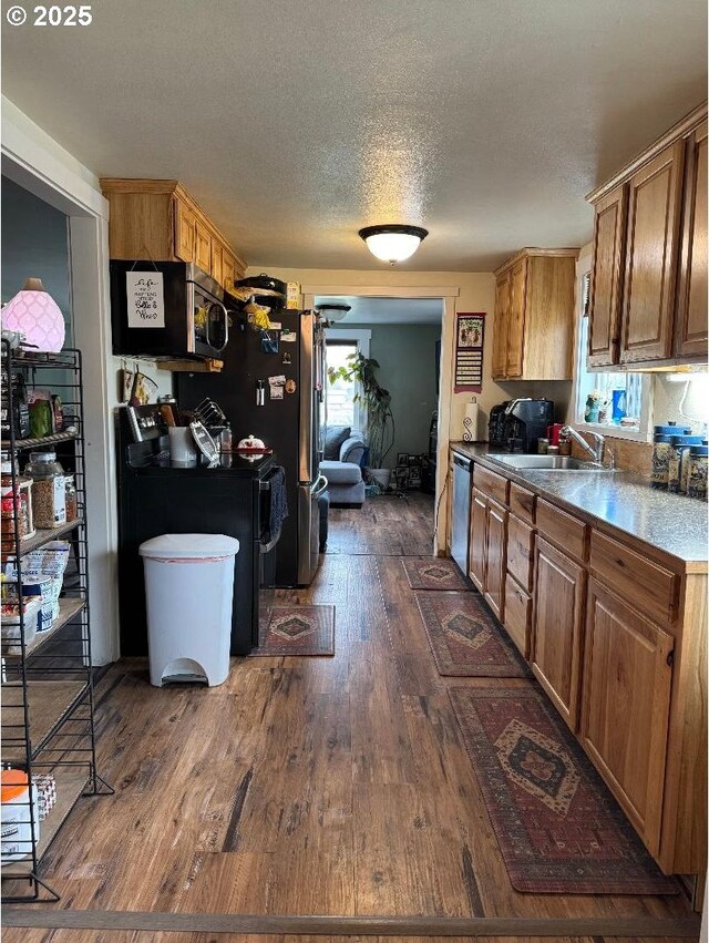 kitchen with brown cabinetry, dark wood-style floors, a sink, and dishwasher