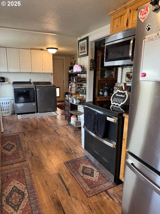 kitchen featuring a textured ceiling, white cabinets, washing machine and clothes dryer, dark wood finished floors, and appliances with stainless steel finishes