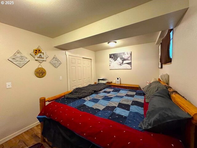 bedroom with baseboards, wood finished floors, and a closet