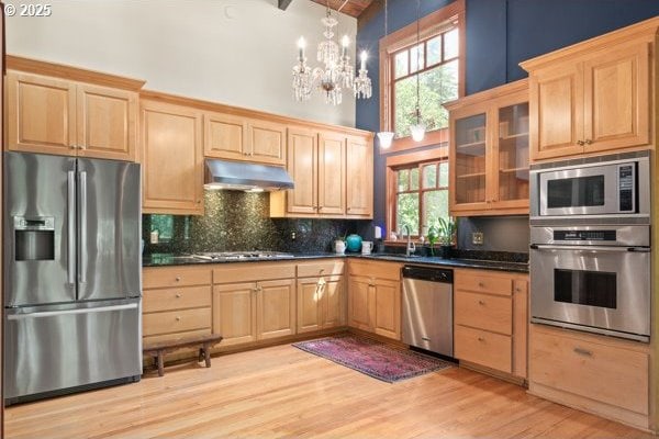 86595 N Modesto Dr, Eugene, OR 97402 - kitchen with appliances with stainless steel finishes, under cabinet range hood, light brown cabinets, high vaulted ceiling, and backsplash