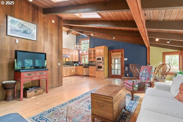 86595 N Modesto Dr, Eugene, OR 97402 - living area with light wood-style floors, wooden ceiling with exposed beams, wooden walls, a skylight, and high vaulted ceiling