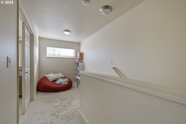 corridor featuring light colored carpet and a textured ceiling