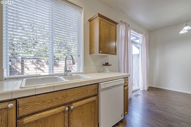 kitchen featuring visible vents, brown cabinetry, dark wood finished floors, dishwasher, and a sink