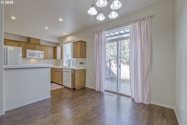 kitchen featuring white appliances, visible vents, brown cabinets, dark wood-style flooring, and a sink