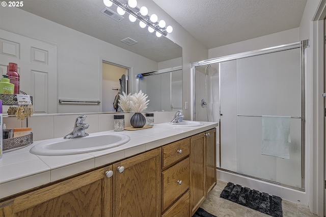 bathroom featuring vanity, backsplash, a textured ceiling, and walk in shower