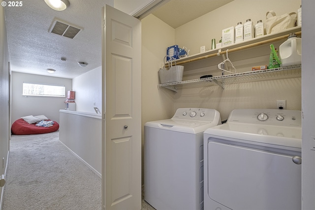 clothes washing area featuring carpet flooring, washer and dryer, and a textured ceiling