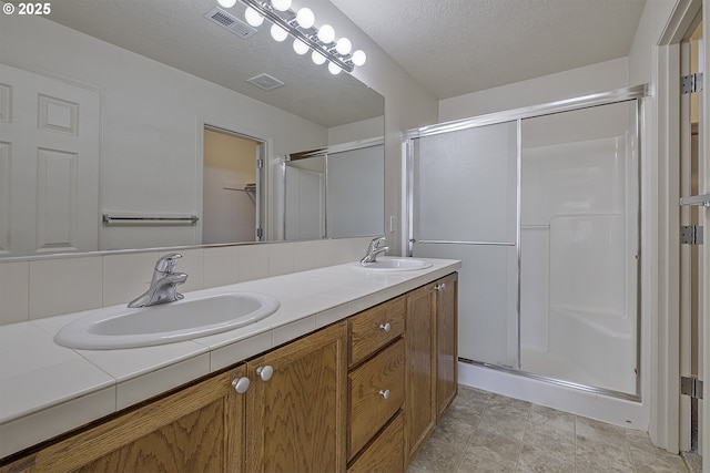 full bath featuring a sink, visible vents, and a shower stall