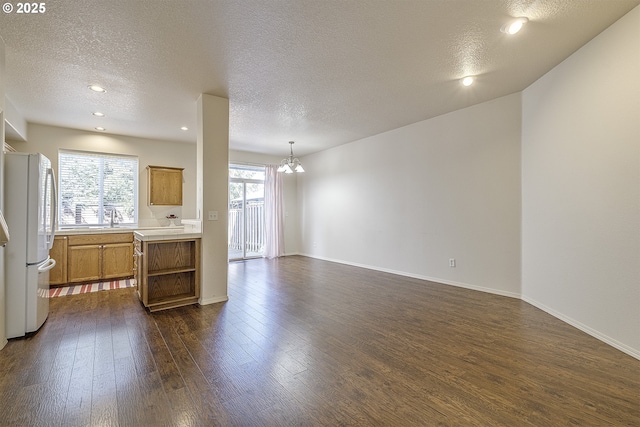 kitchen with dark wood-type flooring, a sink, light countertops, freestanding refrigerator, and brown cabinets