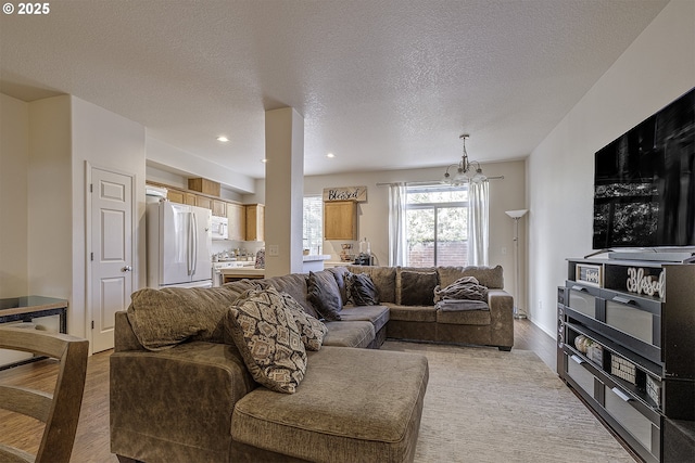 living room with light hardwood / wood-style floors, a chandelier, and a textured ceiling