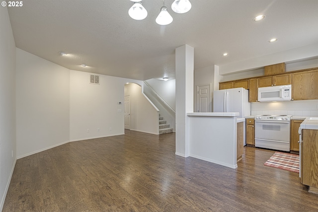 kitchen featuring dark wood-style floors, white appliances, visible vents, and brown cabinets