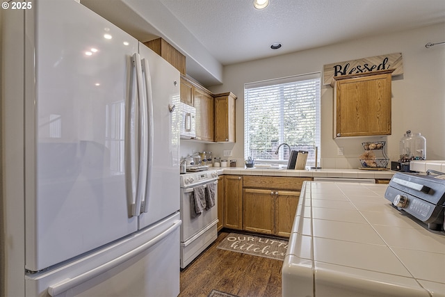 kitchen featuring dark hardwood / wood-style floors, tile counters, a textured ceiling, and white appliances