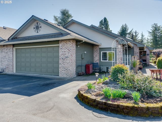 ranch-style house featuring brick siding, an attached garage, driveway, and roof with shingles