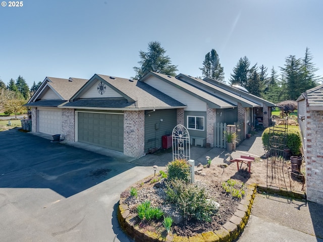 single story home with a garage, brick siding, roof with shingles, and driveway