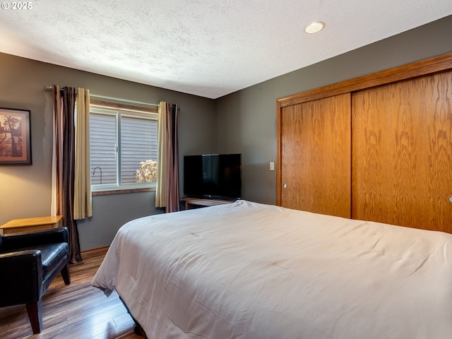 bedroom with a closet, a textured ceiling, and wood finished floors