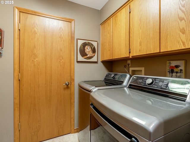 clothes washing area featuring cabinet space and washer and clothes dryer