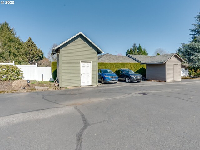 garage with uncovered parking and fence