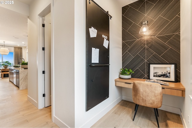 office space with built in desk and light wood-type flooring