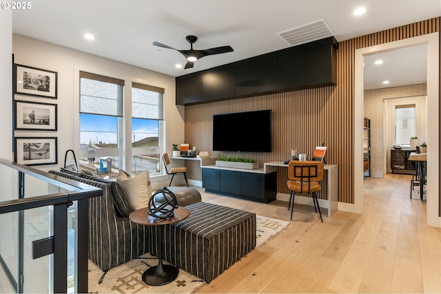 living room featuring ceiling fan, light hardwood / wood-style floors, and brick wall