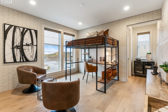 bedroom featuring light wood-type flooring and brick wall