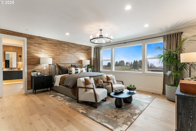 bedroom featuring ensuite bathroom, an inviting chandelier, and light wood-type flooring