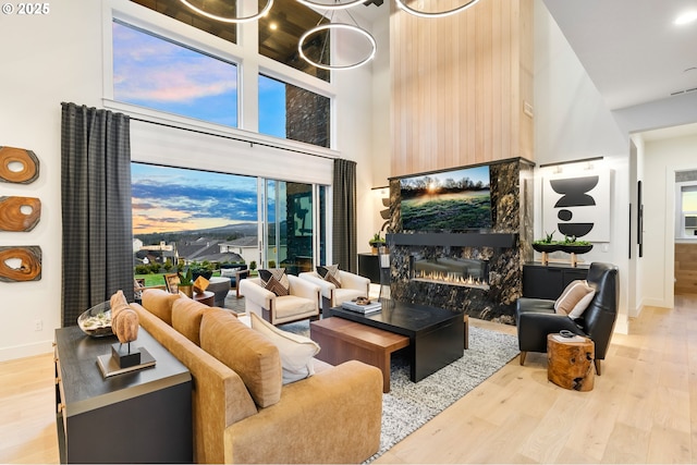 living room with a fireplace, a towering ceiling, and hardwood / wood-style flooring