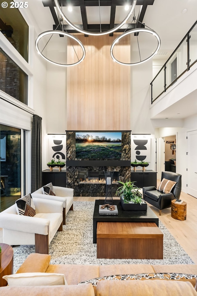 living room featuring a chandelier, a towering ceiling, hardwood / wood-style flooring, and wood walls