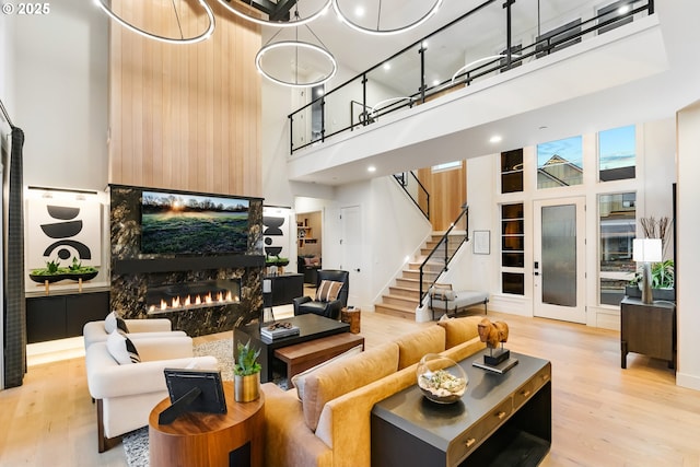 living room featuring a large fireplace, a high ceiling, and light wood-type flooring