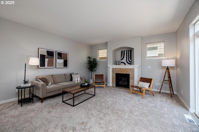 living area with carpet flooring, visible vents, a tiled fireplace, and a wealth of natural light