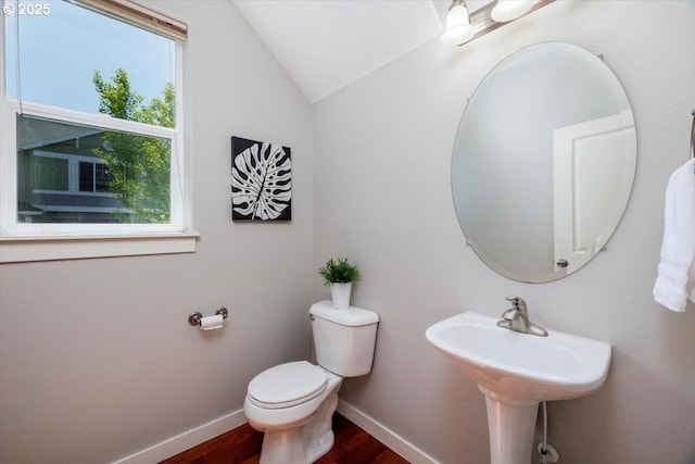 bathroom featuring wood finished floors, baseboards, lofted ceiling, and toilet